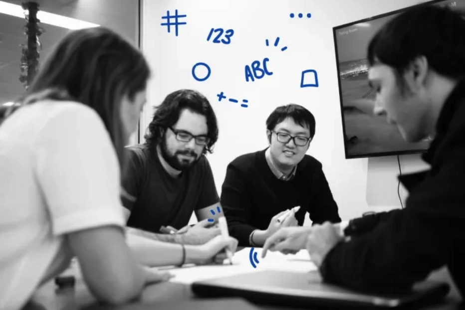 Photo of 4 people at a table discussing the papers in front of them