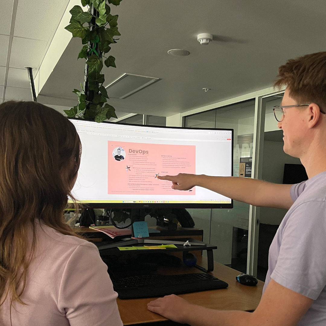 A man and a woman pointing to a computer
