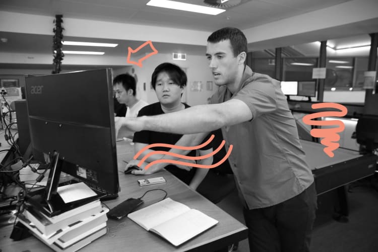 Two men pointing and lookng at a computer screen 