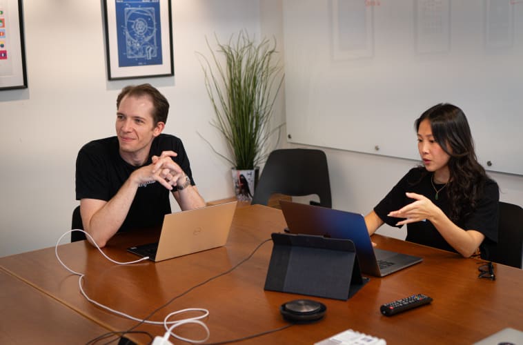 A mana and a woman sitting at a table working on laptops