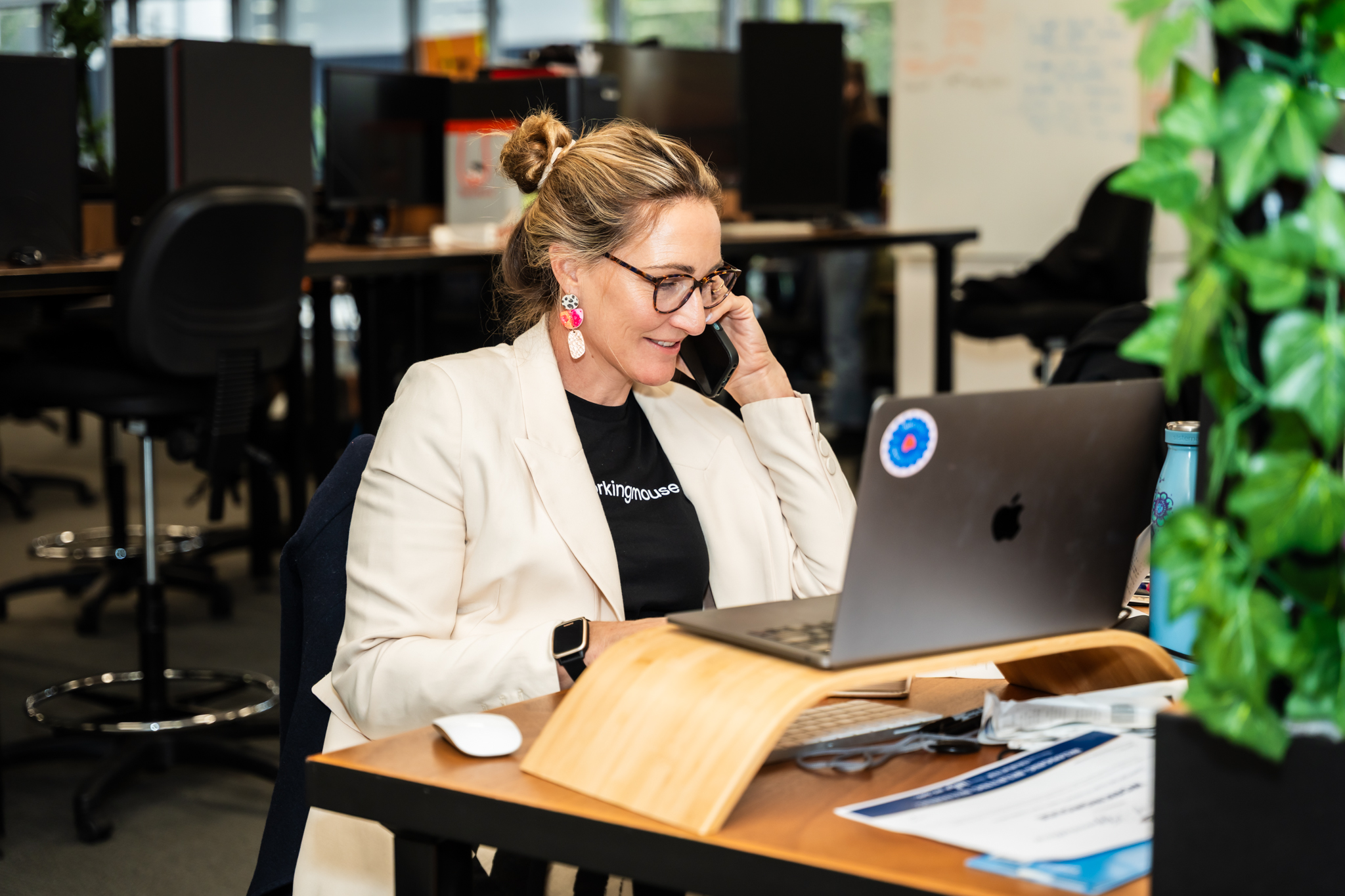 A photo of a women on the phone while working on a laptop