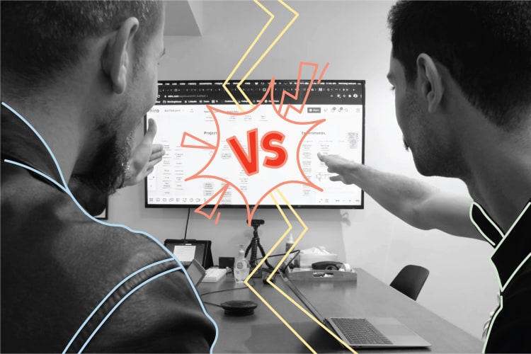 Two men looking and pointing to a computer screen. The word VS is draw onto the image in red and here is a yellow drawn crack down the middle. 