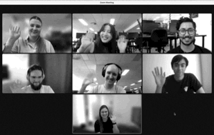 WorkingMouse remote team engaging in a virtual Zoom meeting, with seven team members smiling and waving on screen, showcasing team collaboration and communication in a remote work environment
