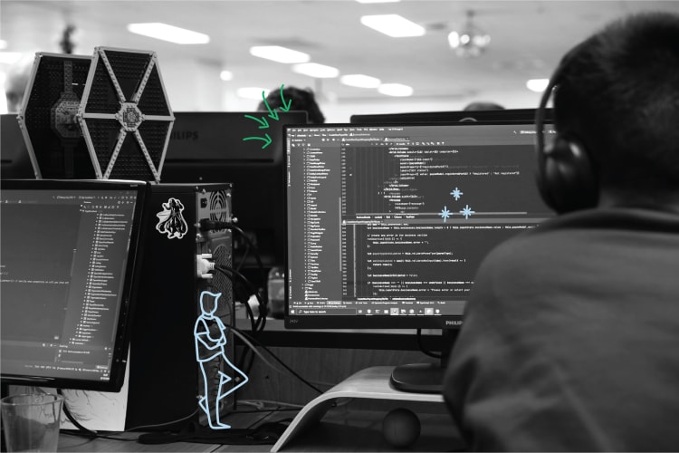 Developer working at a desk with code displayed on multiple monitors, symbolising software development and intellectual property protection in a tech-driven environment.