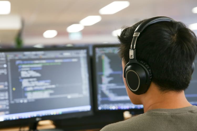 Man with headphones looking at a computer screen