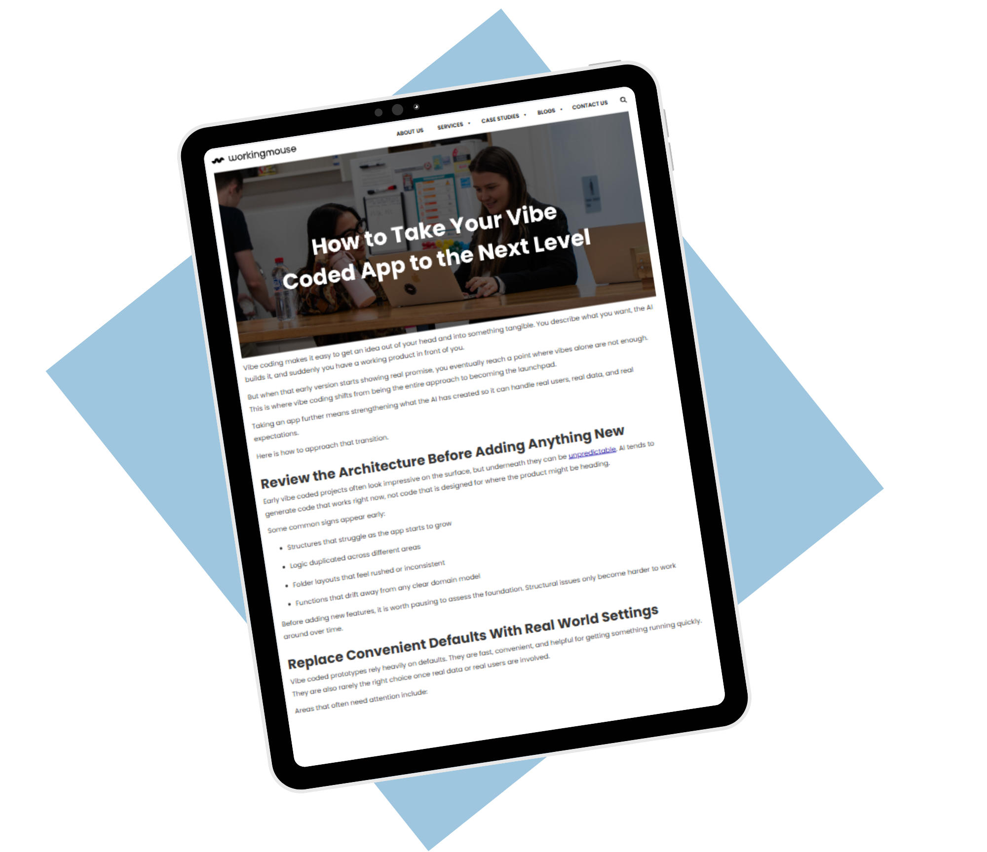 Angled tablet mockup showing a WorkingMouse blog article titled “How to Take Your Vibe Coded App to the Next Level,” featuring a team collaborating around a laptop in an office environment, layered over a dark background with blue geometric shapes.