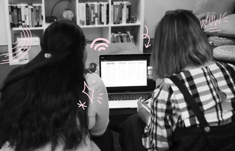 Two women sitting in front of a laptop