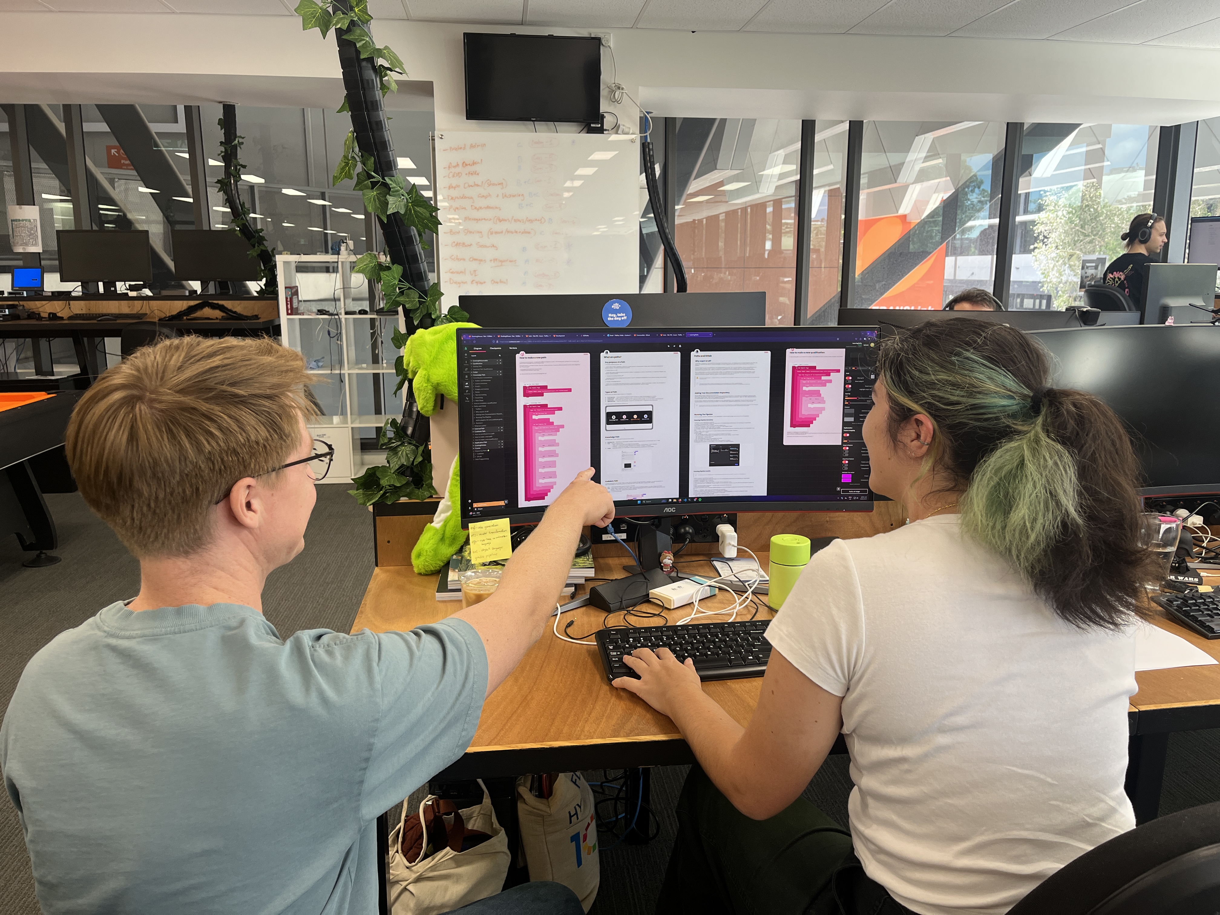 A photo of a man point to a computer screen and a woman sitting next to them